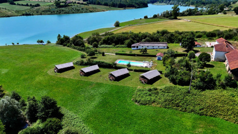 Vue aérienne du Domaine La Barbe en Occitanie, France, avec ses champs verts, piscine et lac à proximité.