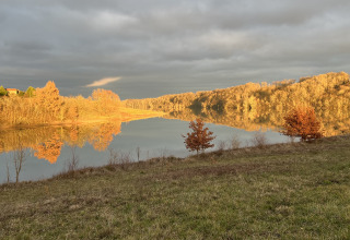 Paysage serein au Domaine La Barbe, Occitanie, France, arbres dorés et reflet miroir sur le lac au crépuscule.