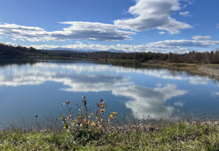 Fredelig udsigt over en sø med spejlede skyer, omgivet af grønne marker i Domaine La Barbe, Occitanie, Frankrig.