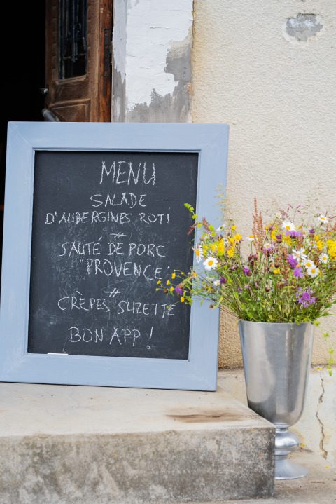 Menubord met Franse tekst naast een vaas veldbloemen bij Domaine La Barbe, Occitanië, Frankrijk.
