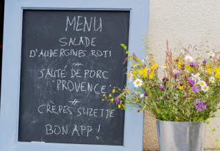 Menu tavle med fransk tekst ved siden af en vase med vilde blomster, Domaine La Barbe, Occitanie, Frankrig.