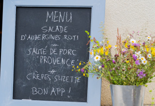 Lavagna con menu in francese accanto a un vaso di fiori selvatici a Domaine La Barbe, Occitania, Francia.