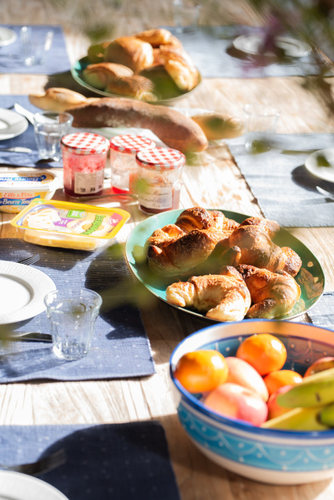 Ontbijttafel buiten rond Lalanne-Arqué, Occitanië, met croissants, fruit, confituur en een stokbrood.