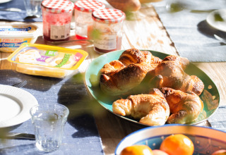 Udendørs morgenbord i nærheden af Lalanne-Arqué, Occitanie, med croissanter, frugt, marmelade og brød.