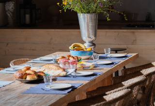 Rustic wooden table set with pastries, flowers, and natural light at Domaine La Barbe, Occitanie, France.