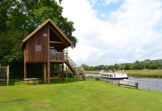 Boomhut met houten trap, picknicktafel en hangmat aan het water bij Camping de Koeksebelt, Overijssel, Nederland.