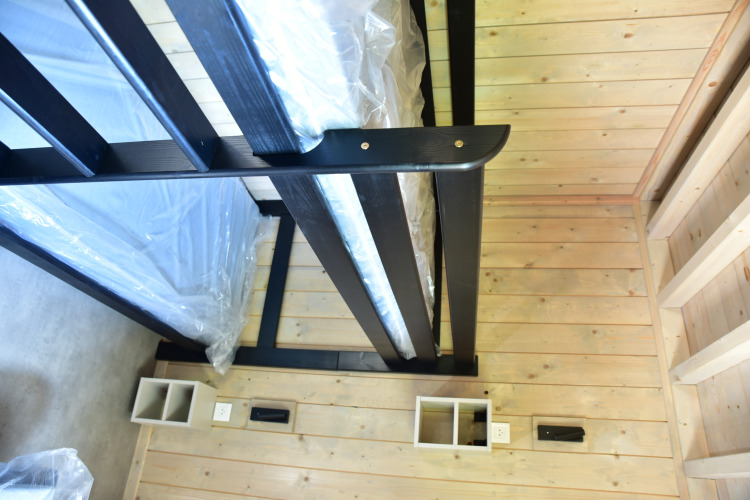 Modern black wooden bunk bed with light wood floors and walls in Ecolodge at Hameau de l'Ourthe, Belgium.