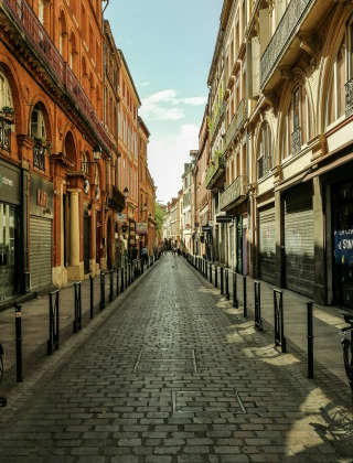 Cobblestone street lined with historic buildings near Lalanne-Arqué in the Occitanie region, France.