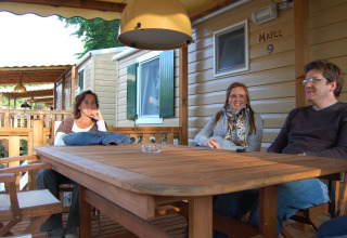 Tres personas sentadas en una mesa de madera frente a SunLodge Maple 9 en Altomincio Family Park, Italia.