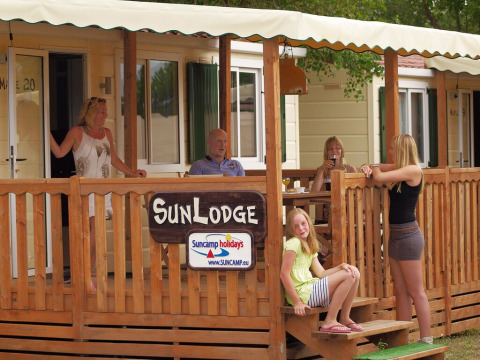 Familia disfrutando en el porche de SunLodge Maple en Altomincio Family Park, Italia, durante sus vacaciones.