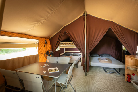 Interno di una tenda Classic presso Huttopia Fontvieille, Francia, con letti, tavolo e sedie.