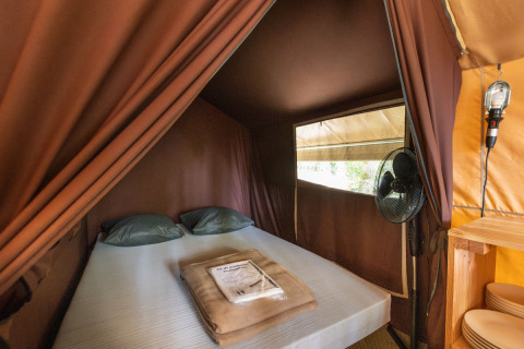 Schlafbereich im Classic Tent bei Huttopia Fontvieille in Frankreich, mit Doppelbett und Ventilator.
