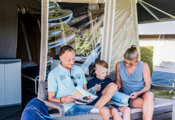 Gezin leest tijdschriften en ontspant op het terras van Auf Kengert Lodge de Luxe in Luxemburg.