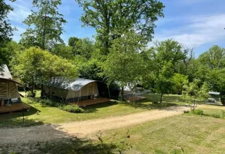 Tiendas rodeadas de árboles en Camping Le Clou, Nouvelle-Aquitania, Francia, en un día soleado de vacaciones.
