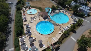 Aerial view of pools and a waterslide at Camping Le Clou, a holiday park in Nouvelle-Aquitaine, France.