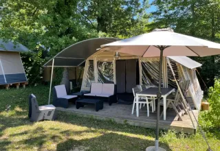 Tenda glamping con area relax e ombrellone a Camping Le Clou, Nouvelle-Aquitaine, Francia.