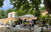 Area esterna con tavoli, sedie e ombrelloni nel Camping Le Clou, parco vacanze in Nouvelle-Aquitaine, Francia.