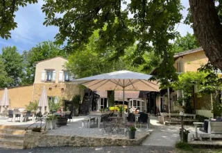 Area esterna con tavoli, sedie e ombrelloni nel Camping Le Clou, parco vacanze in Nouvelle-Aquitaine, Francia.