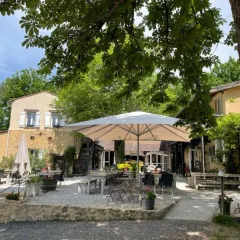 Outdoor dining area with umbrellas and seating at Camping Le Clou, a holiday park in Nouvelle-Aquitaine, France.