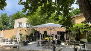 Outdoor dining area with umbrellas and seating at Camping Le Clou, a holiday park in Nouvelle-Aquitaine, France.
