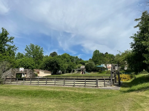 Playground and sports area at Camping Le Clou holiday park in Nouvelle-Aquitaine, France, surrounded by trees.