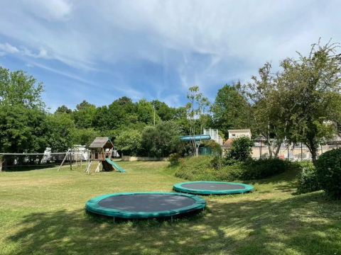 Aire de jeux avec trampolines, balançoires et toboggan au Camping Le Clou en Nouvelle-Aquitaine, France.