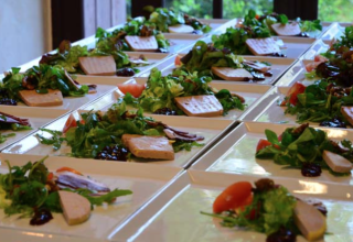 Rows of fresh starter plates with salad and pâté on square dishes prepared for serving at Camping Le Clou.