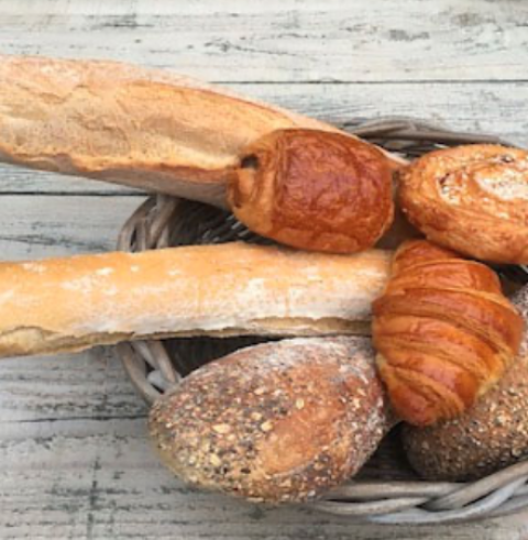 Basket with fresh baguette, croissants, and bread rolls, a highlight at Camping Le Clou in Nouvelle-Aquitaine, France.