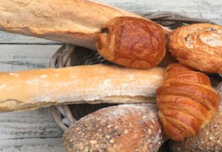 Basket with fresh baguette, croissants, and bread rolls, a highlight at Camping Le Clou in Nouvelle-Aquitaine, France.