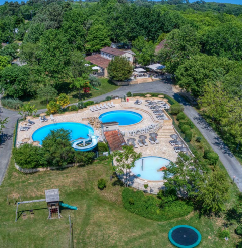 Vista aerea di Camping Le Clou in Nouvelle-Aquitaine, Francia, con piscine, sdraio, area giochi e tanto verde intorno.