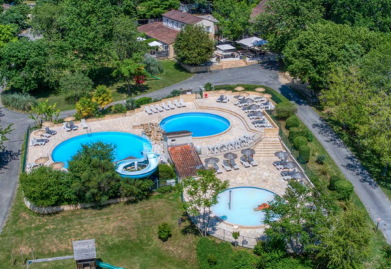 Luftaufnahme von Camping Le Clou in Nouvelle-Aquitaine, Frankreich, mit Pools, Liegestühlen und Spielplatz im Grünen.