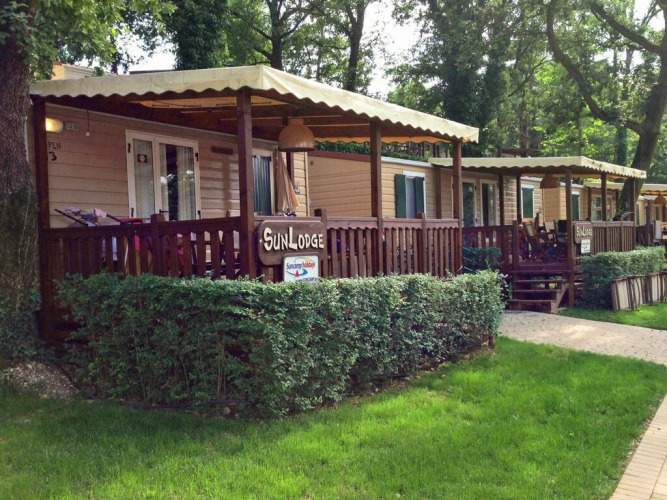 Cabañas SunLodge Aspen con porches cubiertos de madera rodeadas de vegetación y árboles altos.