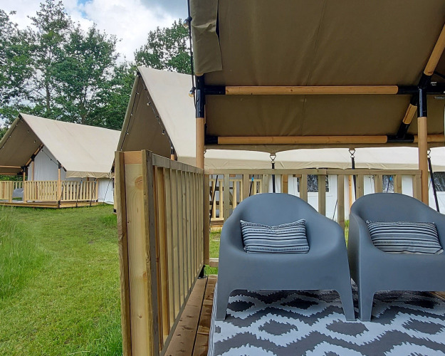 Deux chaises grises sur la terrasse d’une tente safari à Beloofde Land, aux Pays-Bas, en pleine nature.