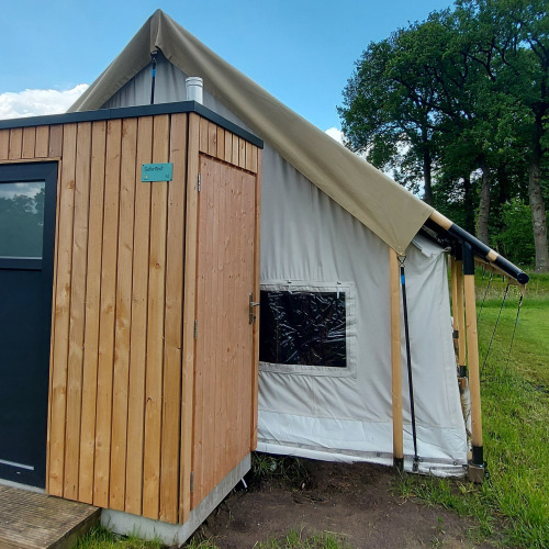 Buitenzicht op Safaritent bij Beloofde Land in Nederland, met houten wanden en stevig canvas dak.