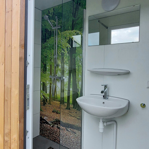 Bathroom inside a safari tent at Beloofde Land in the Netherlands, forest print shower, modern sink.