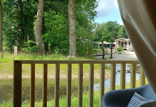 Vue depuis la Safaritent au Beloofde Land, Pays-Bas, montrant la terrasse, des chaises et la nature verdoyante.