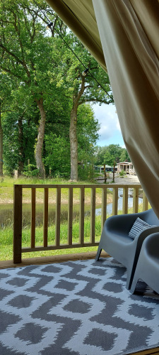 Vue depuis la Safaritent au Beloofde Land, Pays-Bas, montrant la terrasse, des chaises et la nature verdoyante.