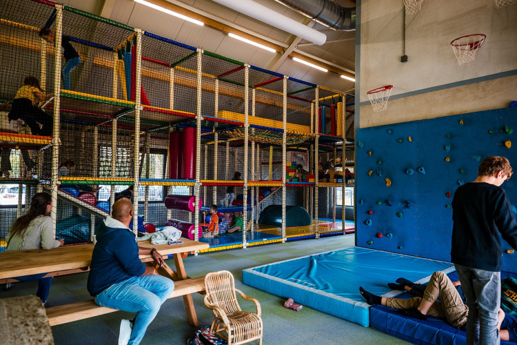 Aire de jeux intérieure au Safaritent Beloofde Land aux Pays-Bas, enfants jouant, adultes assis aux tables.