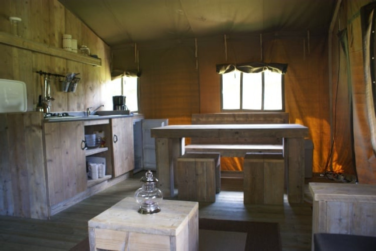 Intérieur de la tente safari Safaritent à Beloofde Land aux Pays-Bas, avec meubles en bois et coin cuisine.