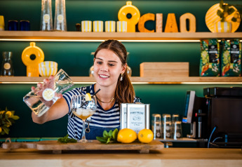 Una barista sorridente versa una bevanda al limone in un bar di glamping dal design moderno.