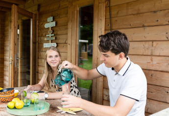 To unge voksne nyder drikkevarer foran en safaritelts hytte kaldet Jungle huisje ved Beloofde Land i Holland.