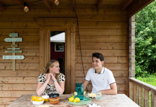 Two young people sit at a wooden table in a safari tent called Lego huisje at Beloofde Land, Netherlands.