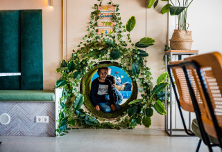 Een jongen speelt in een bladerentunnel bij de Jippi Tippi tent op Beloofde Land in Nederland.