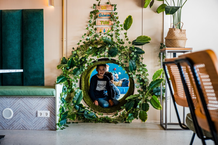 Een jongen speelt in een bladerentunnel bij de Jippi Tippi tent op Beloofde Land in Nederland.