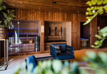 Alojamiento glamping moderno con paredes de madera, saunas de vidrio, asientos cómodos y plantas verdes.