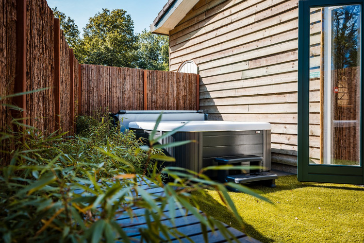 Bain à remous extérieur près d’une tente tipi en bois, entouré de bambous au Beloofde Land, Pays-Bas.