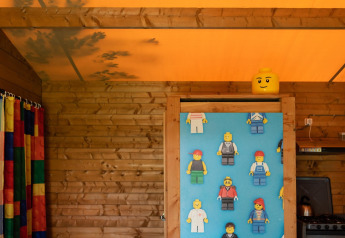 Safari-Zelt mit Holzwänden, buntem Vorhang und LEGO-Figuren im Lego huisje, Beloofde Land, Niederlande.