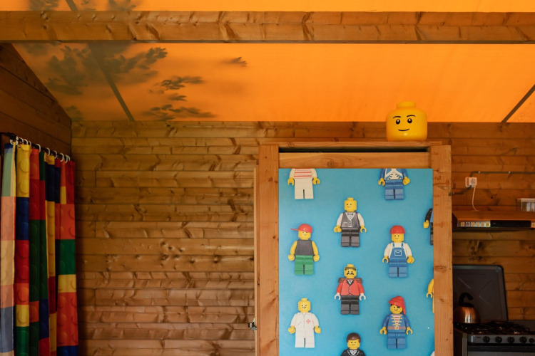 Interieur van safaritent met houten wanden, LEGO-figuren en kleurrijk gordijn in Lego huisje, Beloofde Land.