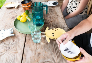 Table set in safari tent Lego huisje at Beloofde Land, Netherlands, with animal-themed plates and glasses.