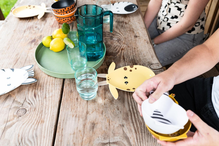 Table set in safari tent Lego huisje at Beloofde Land, Netherlands, with animal-themed plates and glasses.